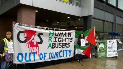 Protestors hold Palestine flags and a large banner that says "G4S: Human Rights Abusers out of our city".